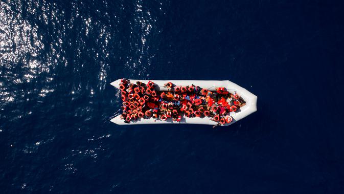 Pengungsi dan imigran mengenakan pelampung saat diselamatkan oleh LSM Proactiva Open Arms Spanyol di utara pantai Libya, Minggu (6/5). Mereka meninggalkan Libya dan mencoba mencapai Eropa. (AP Photo/Felipe Dana)