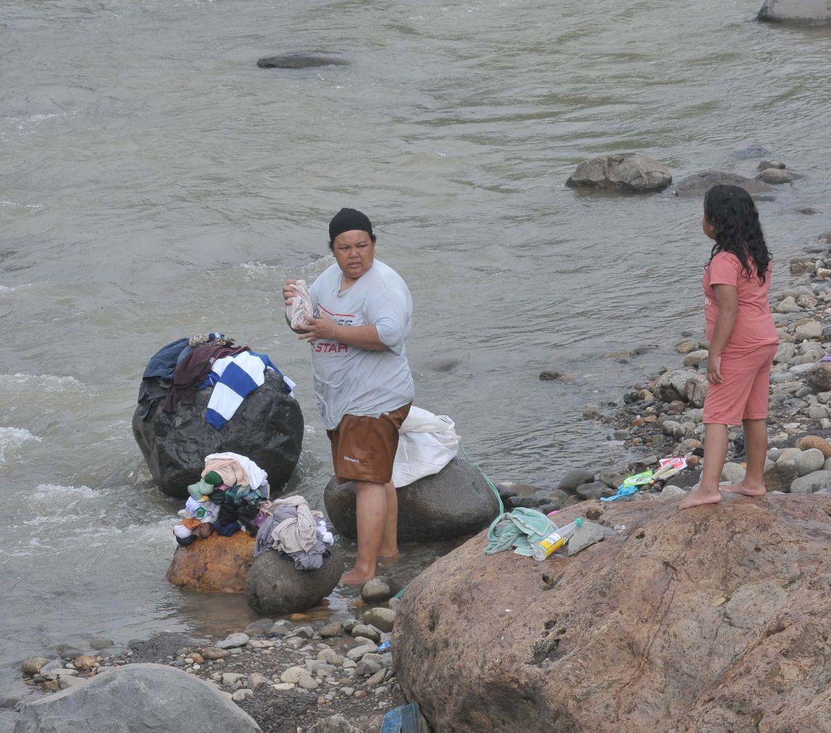 Warga mencuci pakaian di aliran kali Desa Pabuaran, Citeureup, Kabupaten Bogor, Jawa Barat, Jumat (24/5/2024). Sumur-sumur milik warga Desa Pabuaran mulai mengalami kekeringan.&nbsp;Foto: Merdeka.com/Imam Buhori