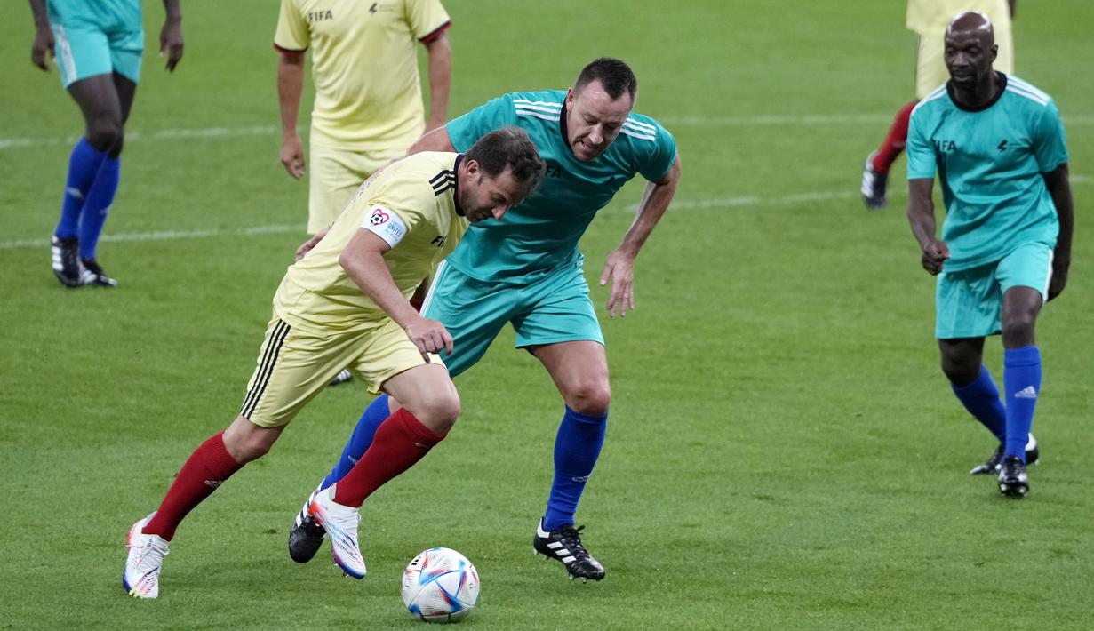 Striker legendaris asal Italia, Alessandro Del Piero, berebut bola dengan bek legendaris dari Inggris, John Terry pada laga hiburan jelang semi final Piala Dunia di Stadion Al Thumama, Senin (12/12/2022). (AP/Frank Augstein)