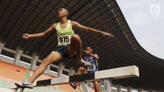 Pelari Sumatra Utara, Loudry Rafael, melakukan lompatan saat Kejurnas Atletik nomor lari 2.000 meter steeplechase putra di Stadion Pakansari, Bogor, Selasa (6/8/2019). Kejurnas tahun ini juga dilakukan untuk kualifikasi menjelang PON. (Bola.com/Vitalis Yogi Trisna)