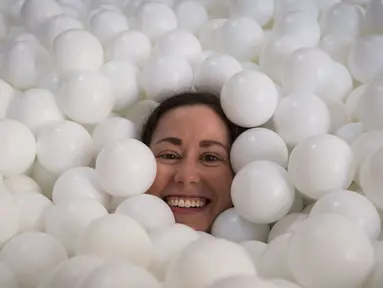 Seorang wanita tersenyum saat tenggelam dalam kolam bola putih di kantor SoHo, New York City, Selasa (25/8/2015). Tempat ini dibuat agar para karyawan dapat bermain dan dapat menhasilkan sesuatu yang kreatif. (REUTERS/Mike Segar)