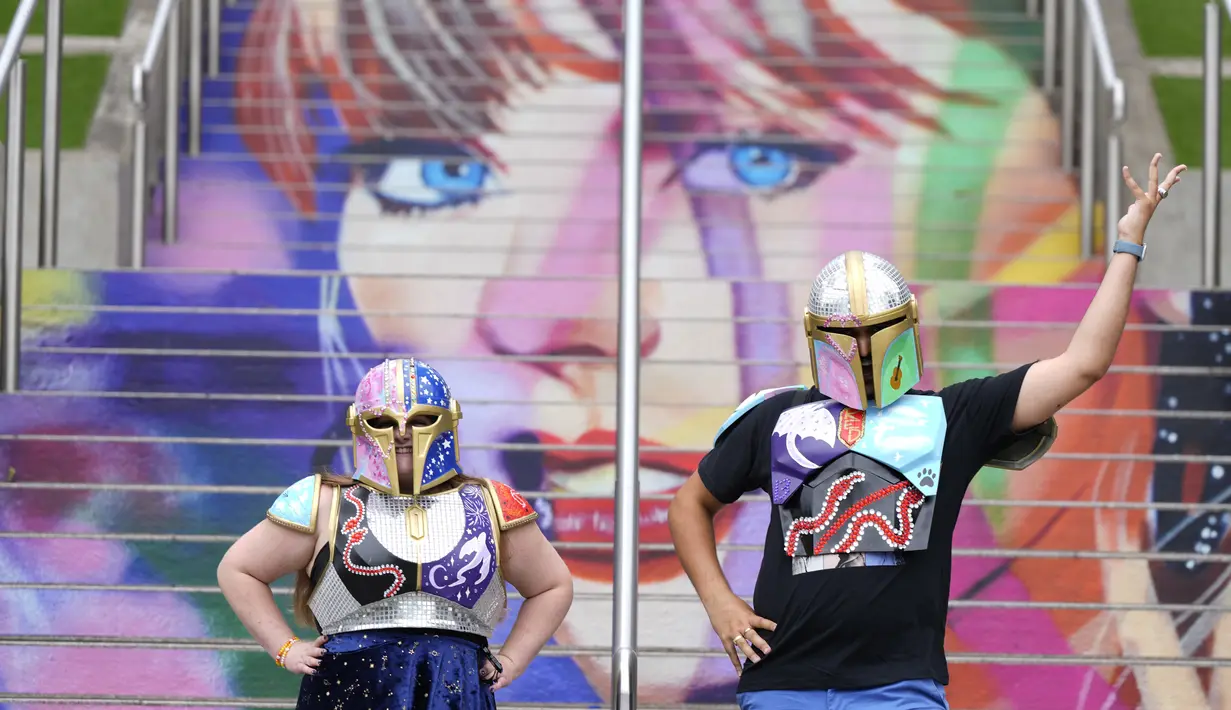 Kristina Broclebanl dan Max Avatar Barnett yang merupakan penggemar Taylor Swift berpose dengan potret Swift yang dilukis di tangga Stadion Wembley menjelang rangkaian konser The Eras Tour di London, Rabu (14/8/2024). (AP Photo/Alastair Grant)